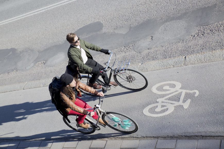Två personer cyklar på cykelväg i Stockholm.