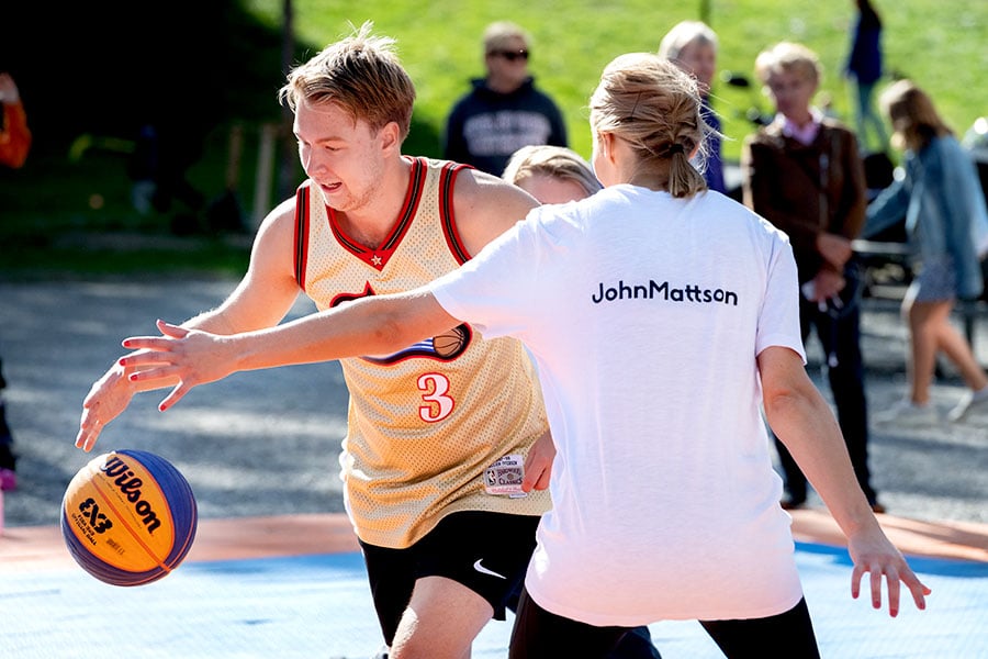 En tjej i John Mattson-tröja blockerar en kille på basketplanen i Larsbergsparken på Lidingö.