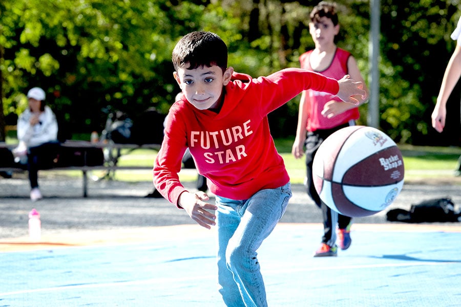 Pojke jagar basketboll i Larsbergsparken på Lidingö.